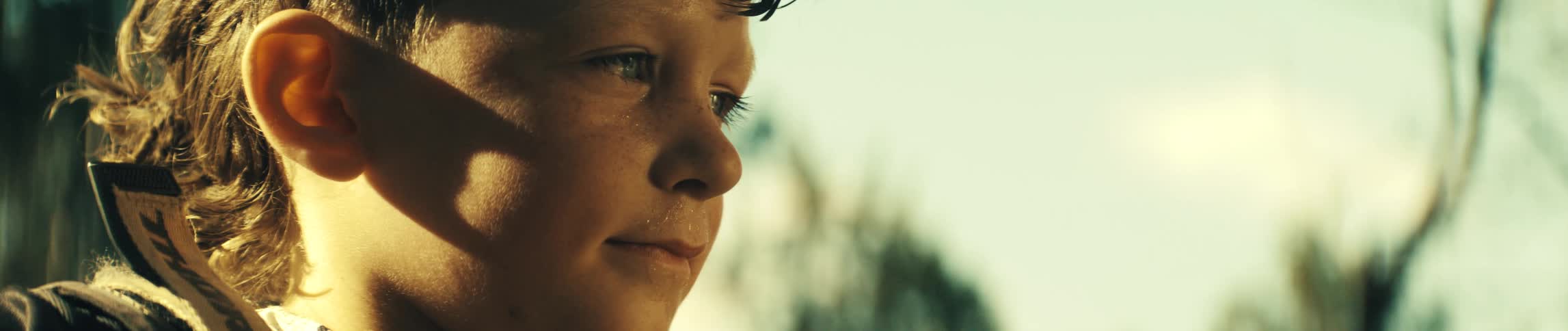 A young boy standing outdoors in the sun