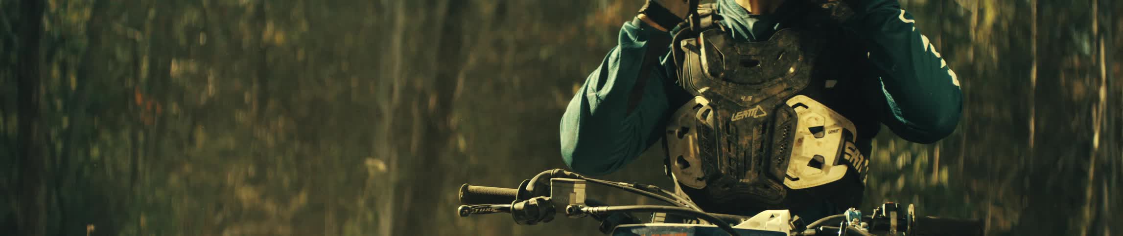 Motorcyclist sits on a motorcycle in the woods on an autumn day