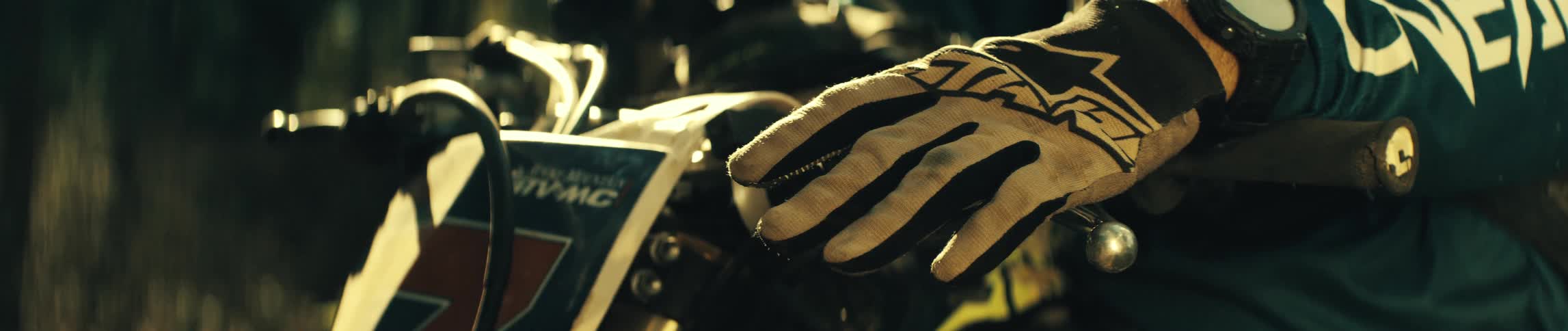 The dirt bike rider is leaning on the handlebars
