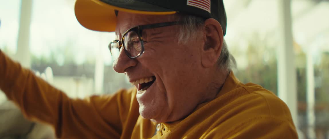 Elderly man at home cheers while watching the tablet that his eyeglasses are reflecting
