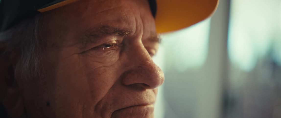 An older mans face with tears in his eyes looking to the side