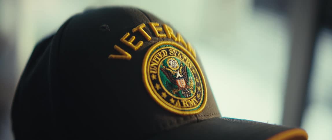 Black and golden baseball cap with text saying veteran and an american seal indoors during day time