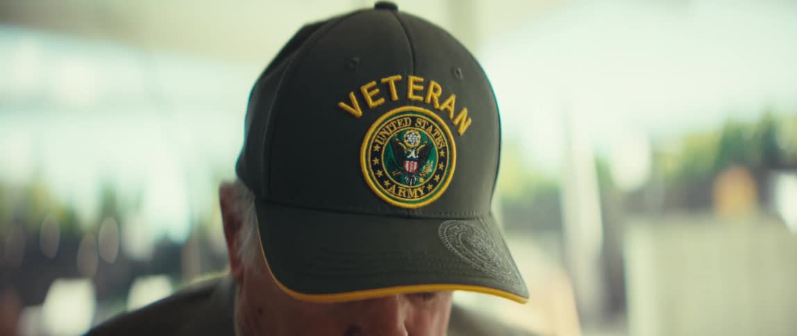 The man is wearing a baseball cap with the word veteran printed on it
