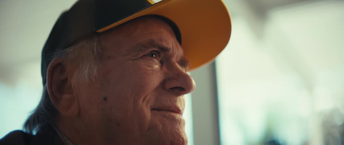 Elderly man wearing a cap with an emotional gaze in an indoor setting