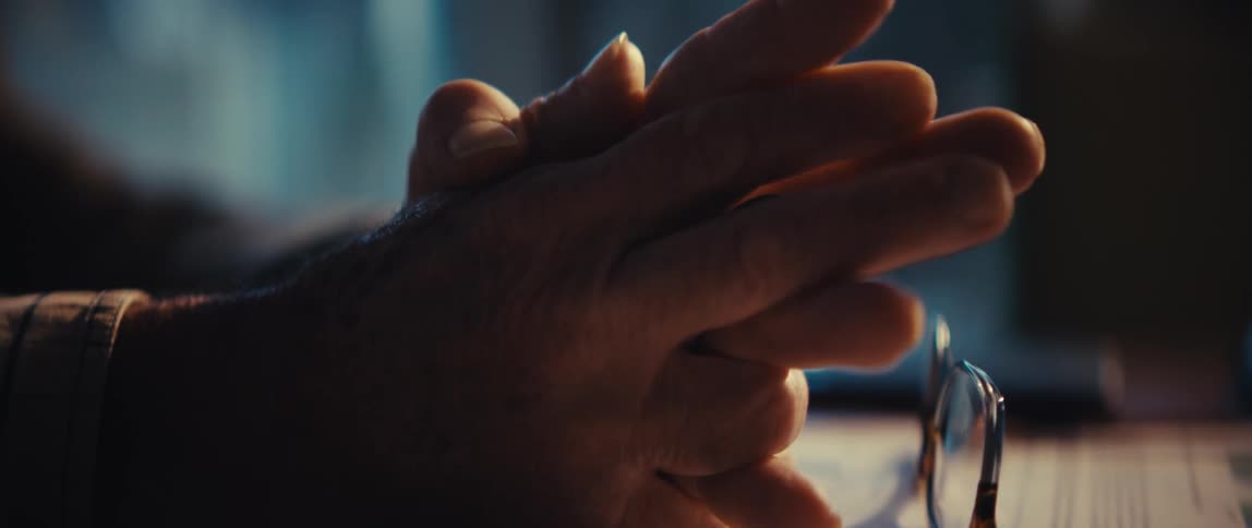 Hands holding pen near glasses on desk