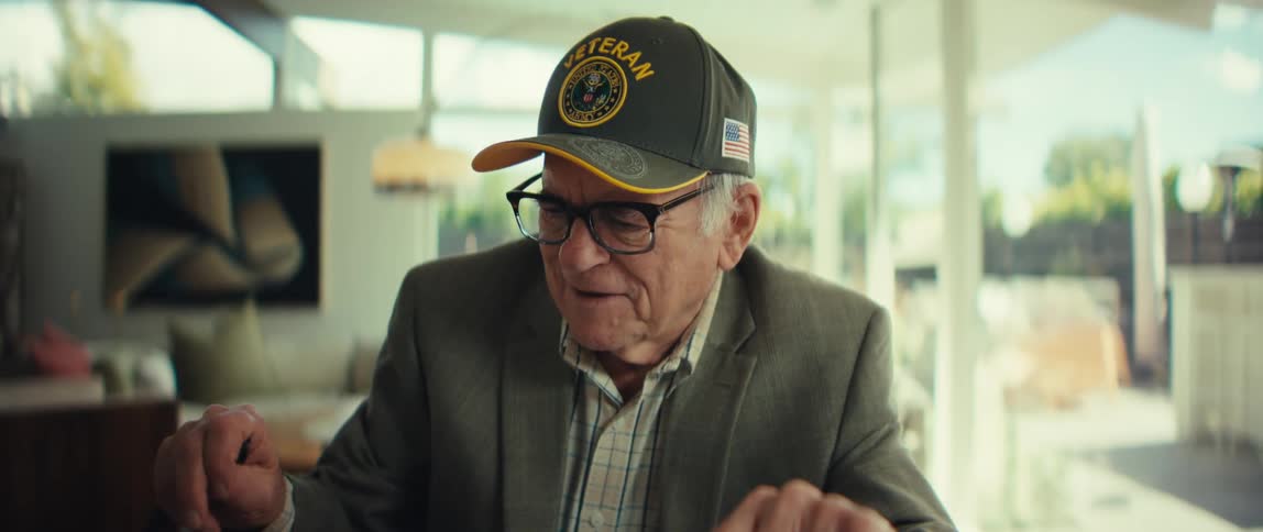 An elderly veteran sits in his living room and celebrates an accomplishment