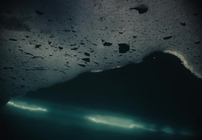 Underwater shot through Ice hole, person in orange on surface