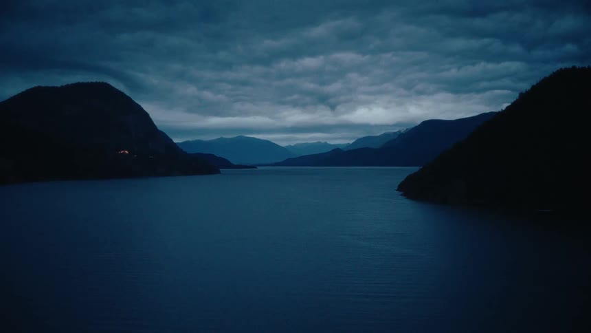 Lake between mountains under a cloudy sky at dusk
