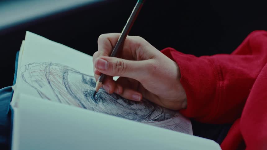 Closeup of a person drawing a mans face on a sketchpad