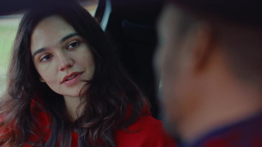 Woman smiling inside a car while talking to a man