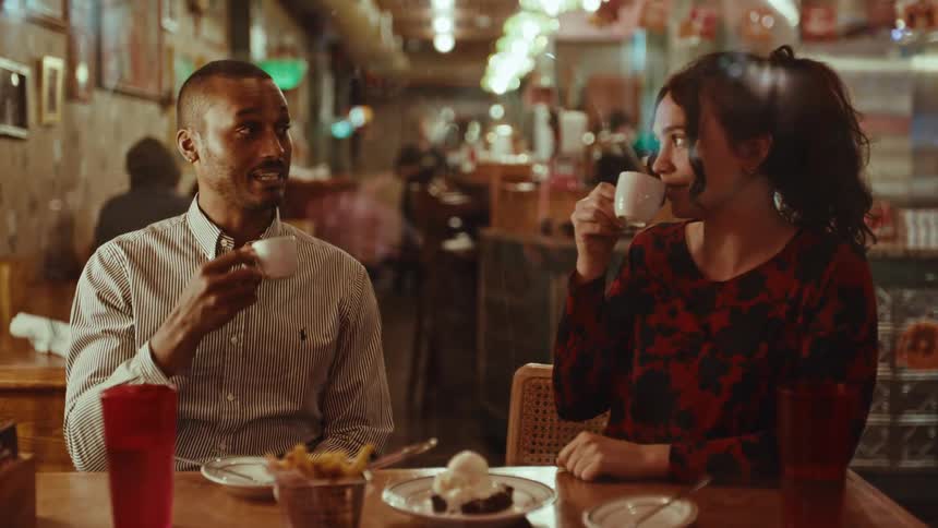 A couple sips coffee as they sit at a table in a restaurant