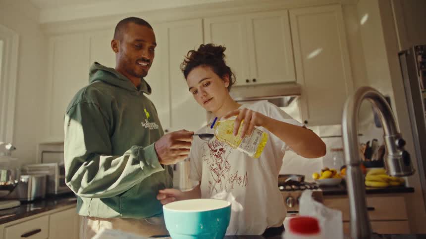 A happy couple are cooking together measuring ingredients in a bright kitchen setting