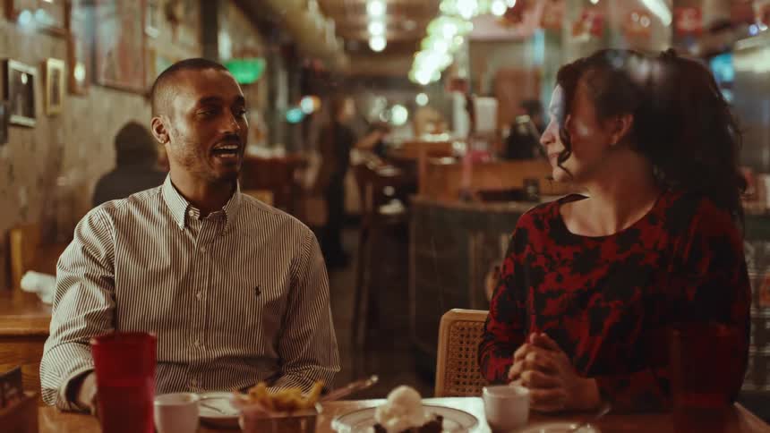 A man and his female companion converse while eating at a diner