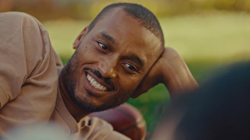 A man is smiling as he lays in the grass