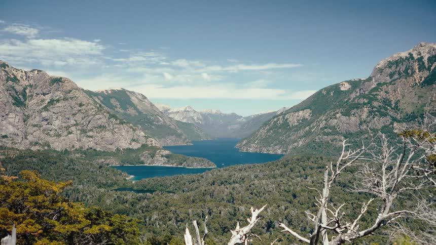 Water winds between forested mountain slopes on a cloudy day