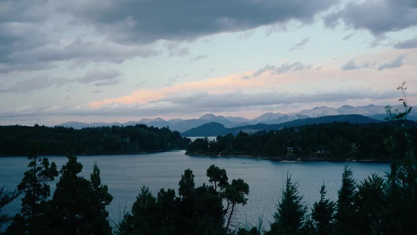 Trees around a lake are blowing in the breeze
