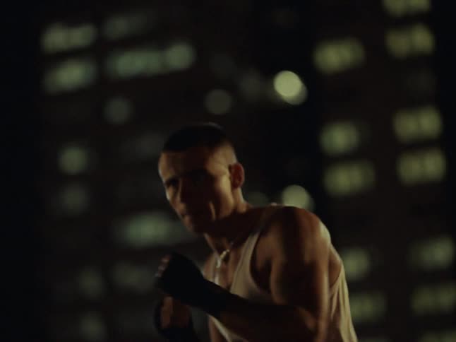 The man is shadowboxing at night in the city
