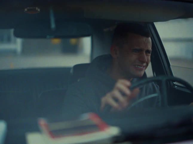 A man driving a car and slapping the steering wheel