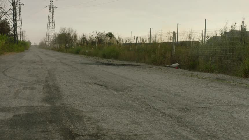 Road passes between electric transmission towers while passing a manufacturing plant