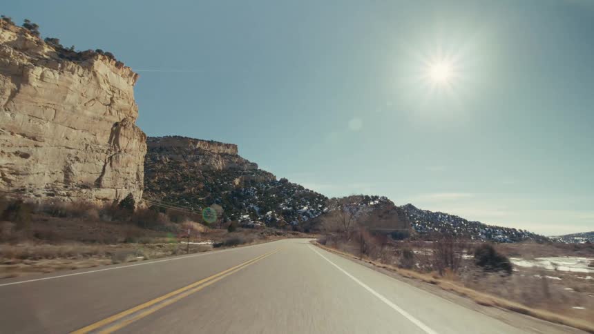 A road trip on a freeway on a sunny winter day with mountains along the side of the road