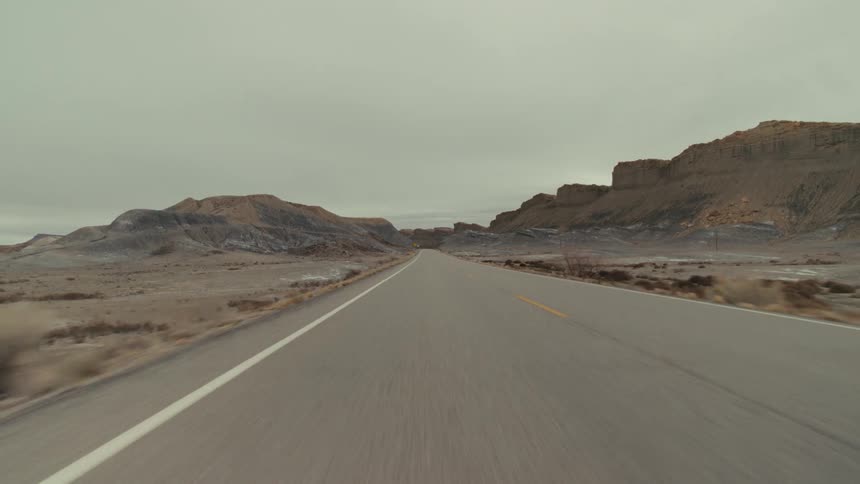 Traveling along a roadway that passes by a barren landscape