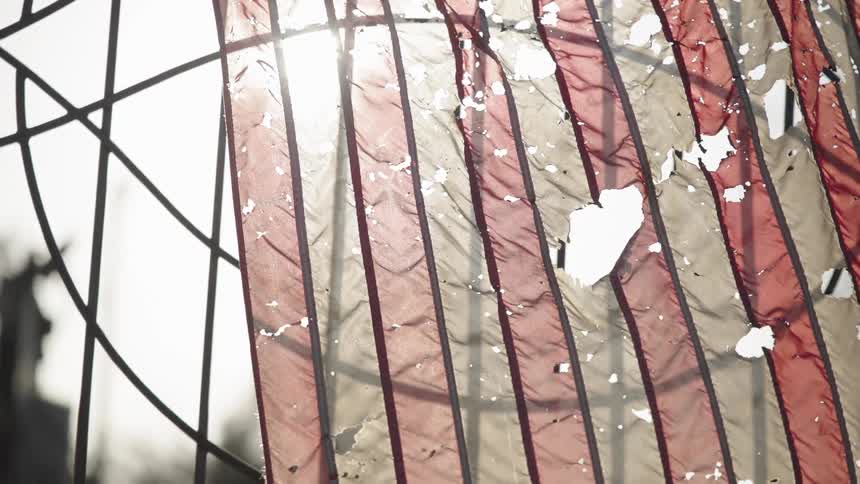 Tattered stripped fabric hangs on an ironwork gate during the daytime