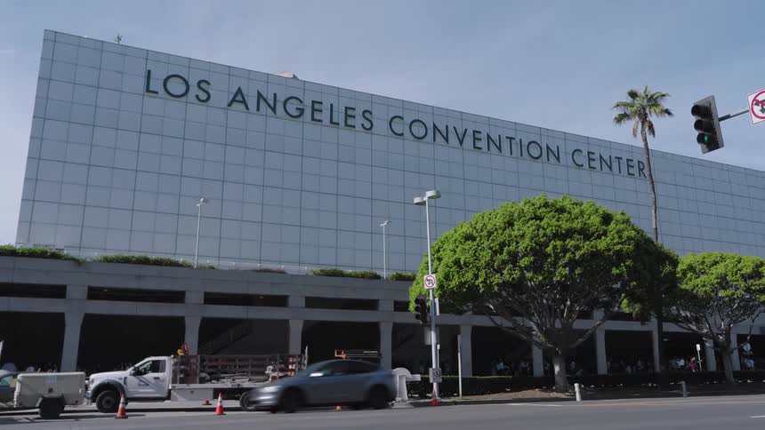 Car passes the los angeles convention center building and a parked truck