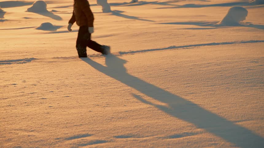 A man is walking on a path through the snow