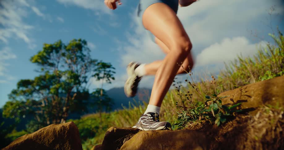 A woman is running up a trail on a mountain