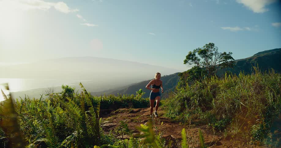 Woman swings her arms as she runs on a mountain trail
