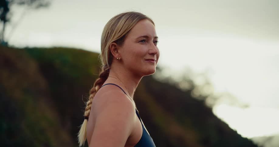Woman smiles and turns her head as she stands on a mountain