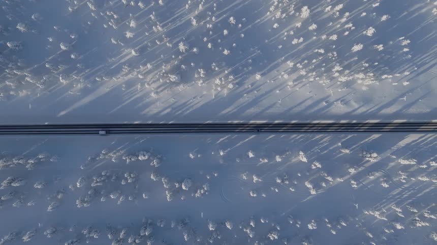 An aerial view of a road in the middle of a forest covered in snow
