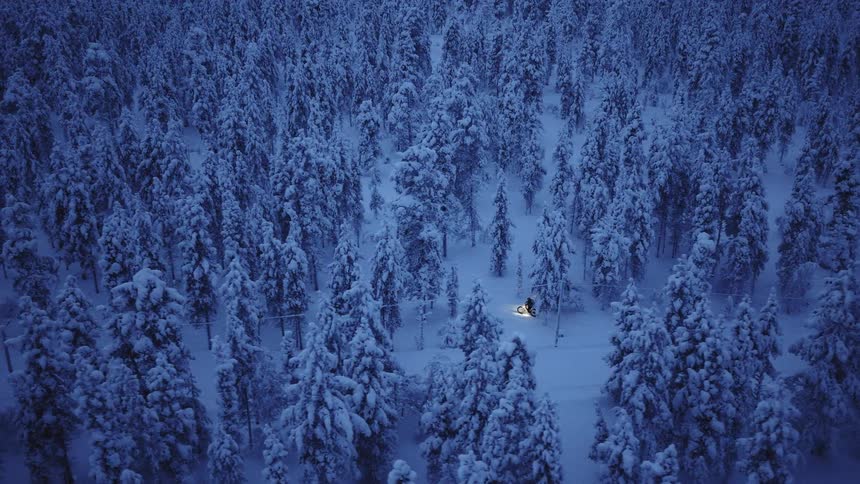 A person rides a bicycle through think snow that has fallen on a forest