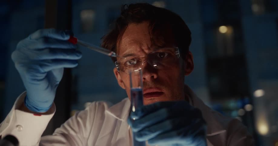 Researcher wearing gloves and safety goggles uses a pipette to add liquid into a test tube