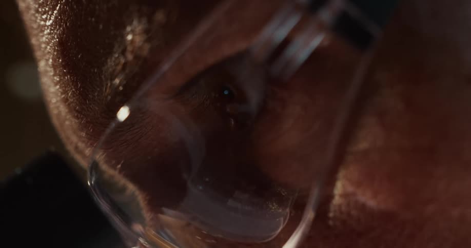 An extreme close up of a man wearing goggles looking intently through a microscope