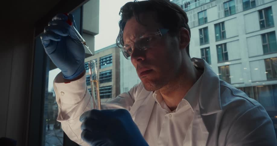 Man works in a laboratory with a dropper and a test tube
