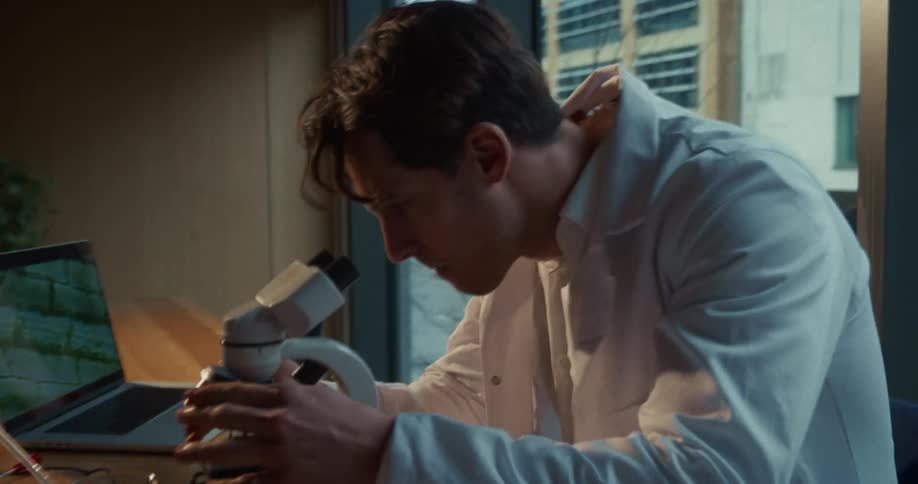 A man looking through a microscope in a lab