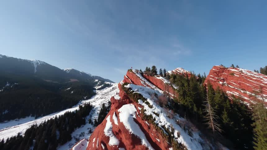 Winter landscape with snowcovered red rock formations in the foreground in the background there are mountains and a forested valley