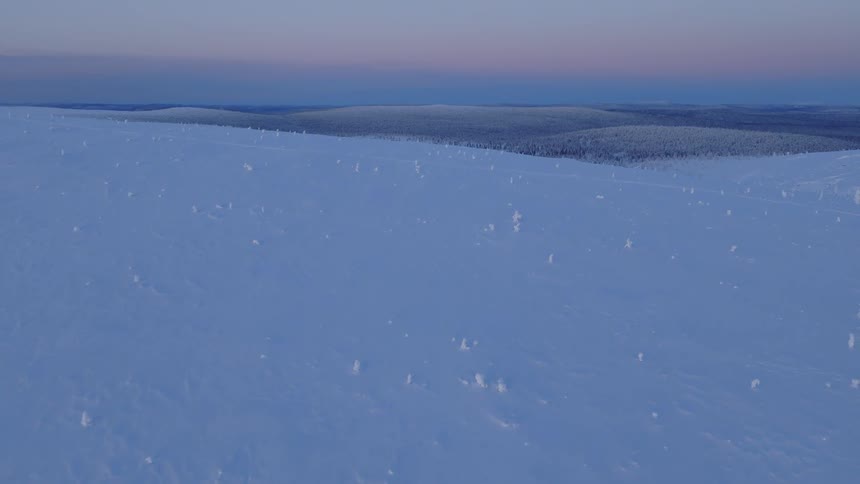 Aerial view of a snow covered mountain slope at dusk