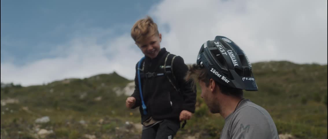 Son puts a helmet on his father backwards then laughs and claps