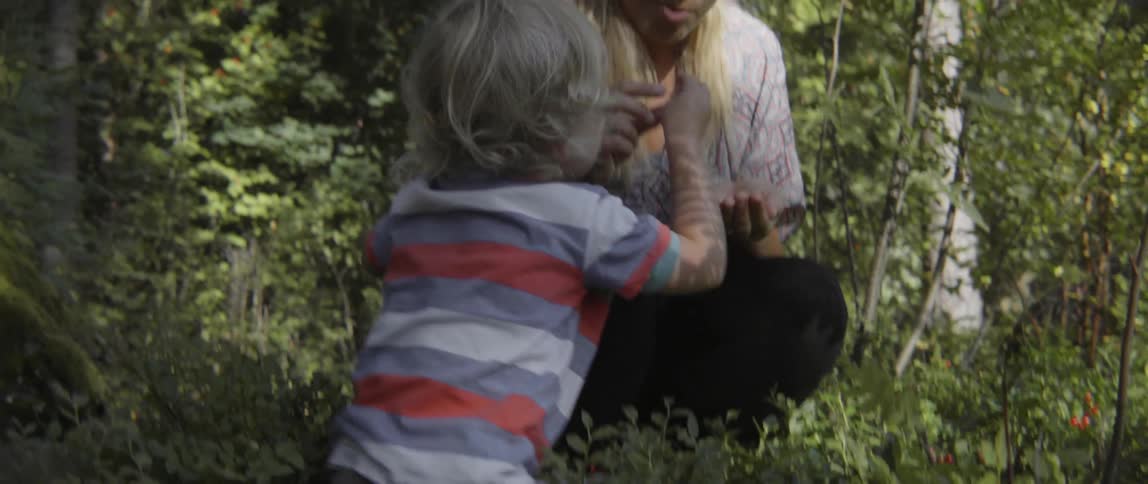 Woman eating berries that her child is picking outdoors