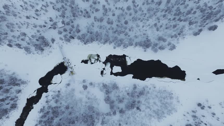The small stream runs through the snow covered forest