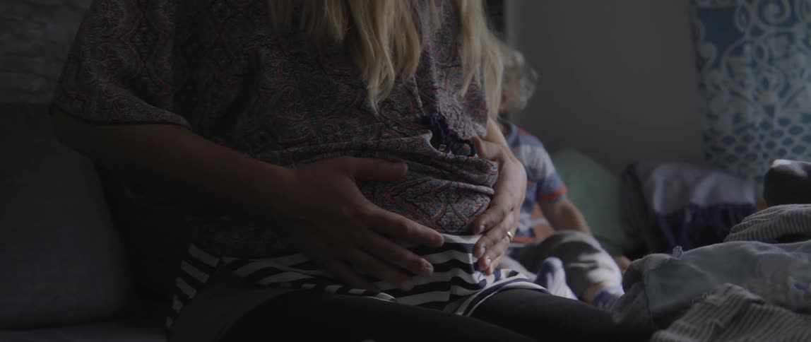 Expectant mother and toddler boy bonding together while sitting in a bright room.