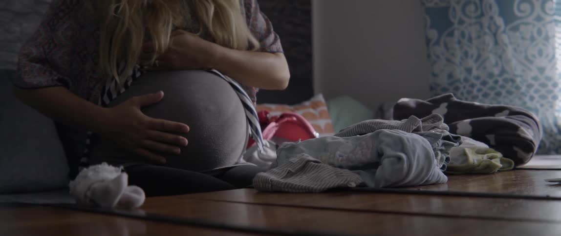 Heartwarming footage of a pregnant woman touching her belly in a bright living space.
