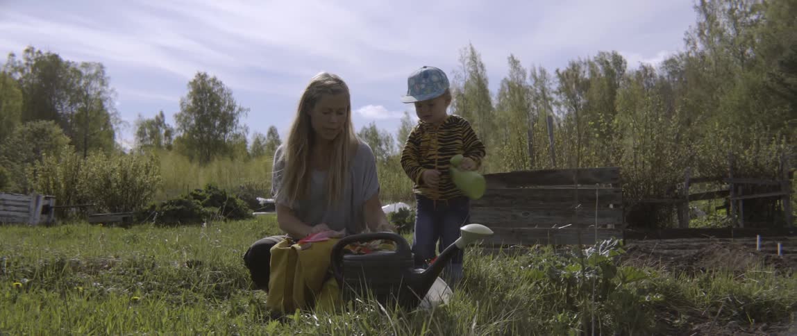 Mother and son working together in a lush outdoor garden during the day