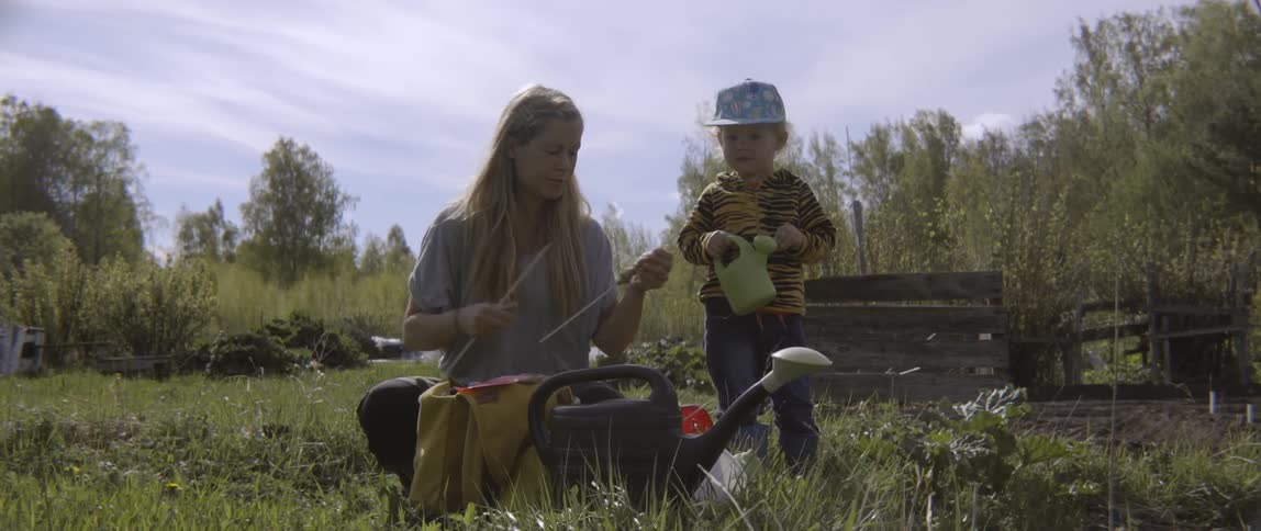 A woman and her toddler child are outside working in a garden