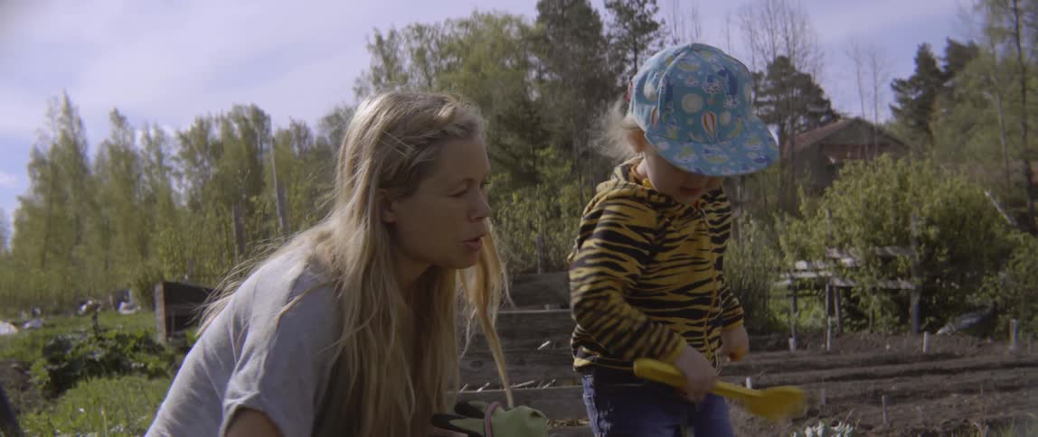 Young boy and woman engaging in outdoor gardening activities during a sunny day.