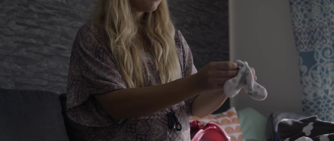 Woman folds two small mittens and puts them next to other laundry