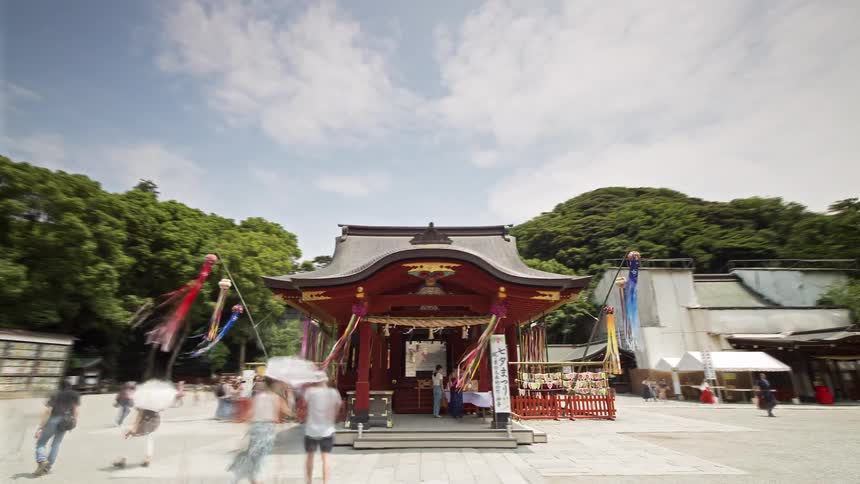Japanese shrine with a red structure in an open courtyard surrounded by trees and hills