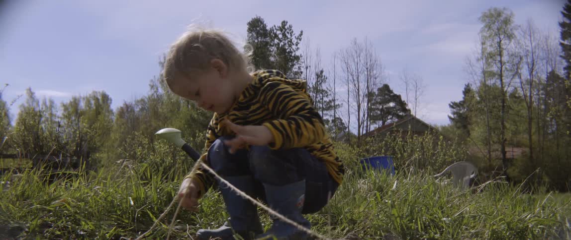 Child touching a stringed boundary line in a field on a cloudy day